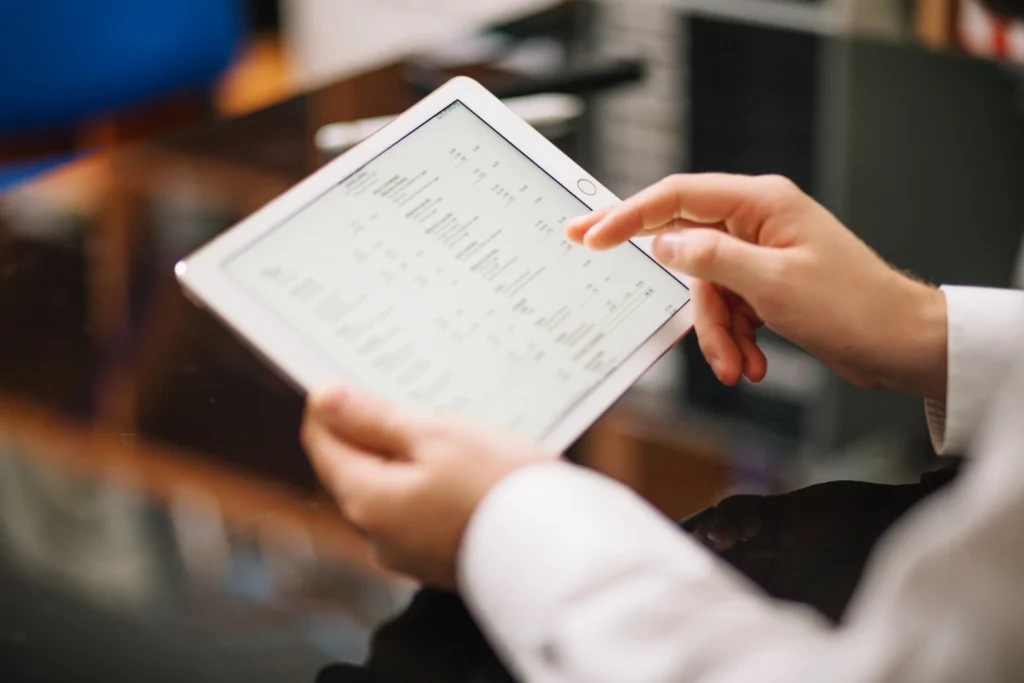 Mani maschili che tengono un tablet con sopra cifre e numeri del controllo di gestione